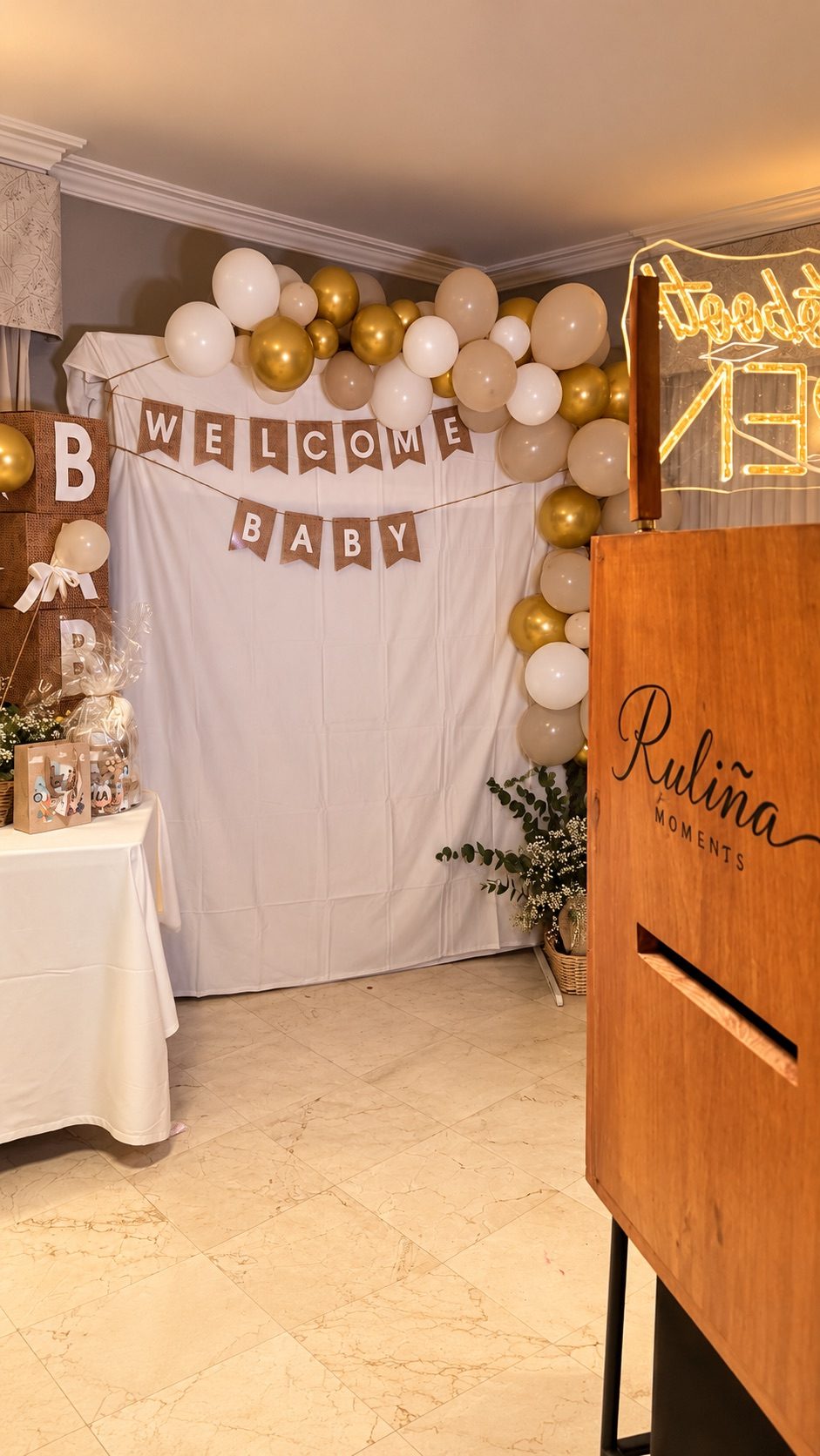 Rincón de baby shower en Ourense con arco de globos dorados y beige, banderines Welcome Baby y fotomatón de madera de Ruliña Moments
