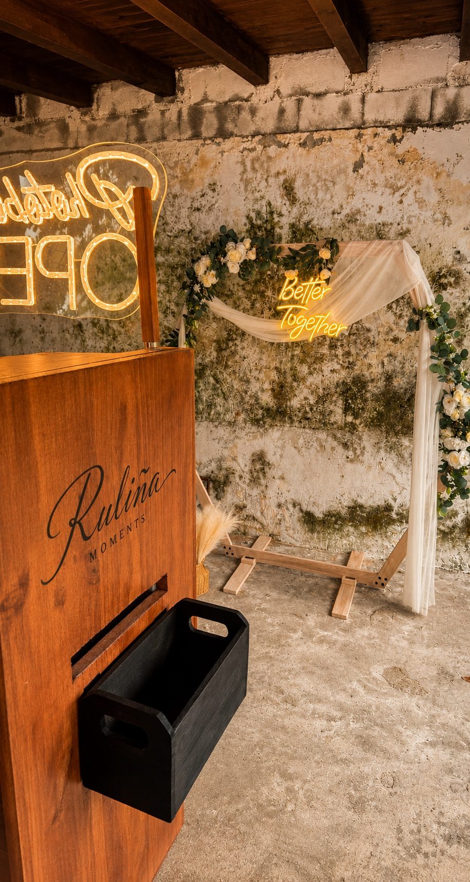 Mueble del fotomatón con logo y arco decorativo en salón de piedra · Ruliña Moments